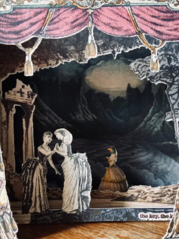 Image of a paper theatre card pop-out with background of mountains and sea/sky combined, middle layer of a classical scene with temple and trees, and curtains. Two victorian women, one with curled goats horns, clasp hands on layer 2. A woman with a bird head can be seen in the distance. Text can just be glimpsed 'the key'